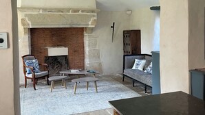 A cozy living room with a fireplace, a sofa, a coffee table, and a dining area with a cabinet.