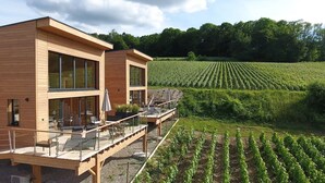 Un bâtiment moderne en bois, doté de grandes fenêtres et d’un balcon donnant sur un vignoble.
