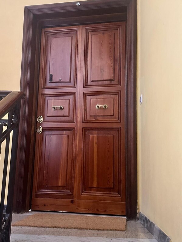 A wooden door with a keypad lock and a keyhole, leading to a staircase.