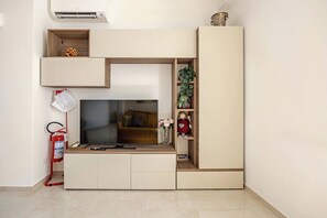 A modern living room with a flat-screen TV, built-in shelves, and a fire extinguisher.
