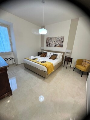 Ein Hotelzimmer mit einem Bett, einem Schreibtisch, einem Sessel und einem Gemälde an der Wand.