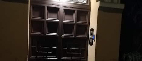 Een donker houten deur met een decoratief glasraam erboven, geplaatst in een stenen boog.