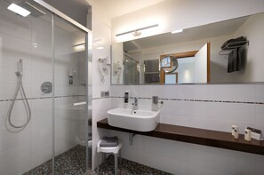 A modern bathroom with a glass-enclosed shower, a white sink, and a large mirror.