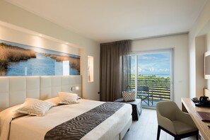 Une chambre d’hôtel avec un grand lit, un bureau et un balcon offrant une vue agréable.