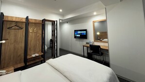A hotel room with a bed, a desk, a chair, a TV, a wardrobe, and a mirror. - Afsona hotel (Qarshi)