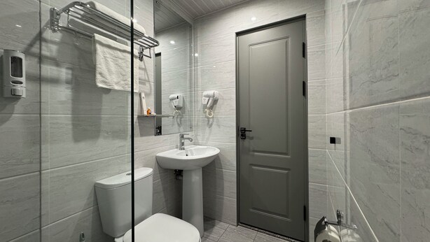 Une salle de bain moderne équipée de toilettes, d’un lavabo et d’un porte-serviettes.