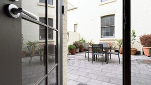 An outdoor patio with a table and chairs, surrounded by potted plants. - Cameron Mews: In The Heart Of The City (Launceston City)