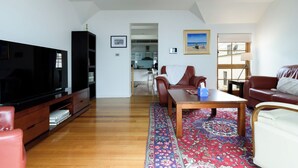 A living room with a TV, leather sofas, a coffee table, and a patterned rug. - Cameron Mews: In The Heart Of The City (Launceston City)