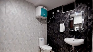 A bathroom with a toilet, a sink, a mirror, and a hand dryer. - Blessings Imperia (Prayagraj)