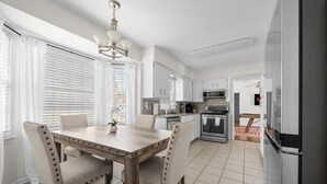 A kitchen with a dining table, chairs, and a refrigerator. - Serene Pool retreat w/ Games Near Fort Moore (Columbus)