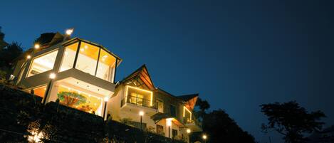 A modern house with a glass facade, multiple balconies, and a sloped roof.
