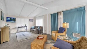 Amplia sala de estar con un sofá, dos sillones, una mesa de centro y un comedor con mesa y sillas.