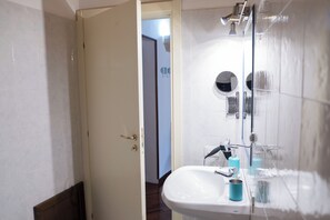 Uma casa de banho com uma pia branca, um espelho e um chuveiro.