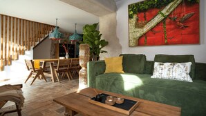 A cozy living room with a green sofa, wooden dining table, and hanging lights. - Between the mountains and the sea, a profound and eco-chic nature experience in (Montbolo)