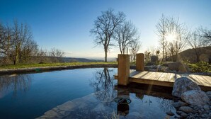 A serene outdoor pool area with a wooden deck, surrounded by trees and a clear sky. - Between the mountains and the sea, a profound and eco-chic nature experience in (Montbolo)