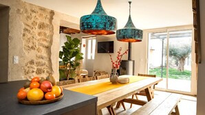 A modern kitchen with a stone wall, wooden table, and hanging blue pendant lights. - Between the mountains and the sea, a profound and eco-chic nature experience in (Montbolo)