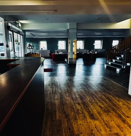A spacious room with a wooden floor, a long counter, and a staircase.