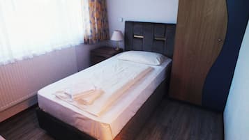 Una cama bien hecha con una toalla doblada, una lámpara de noche y un cabecero de madera en una habitación de hotel.