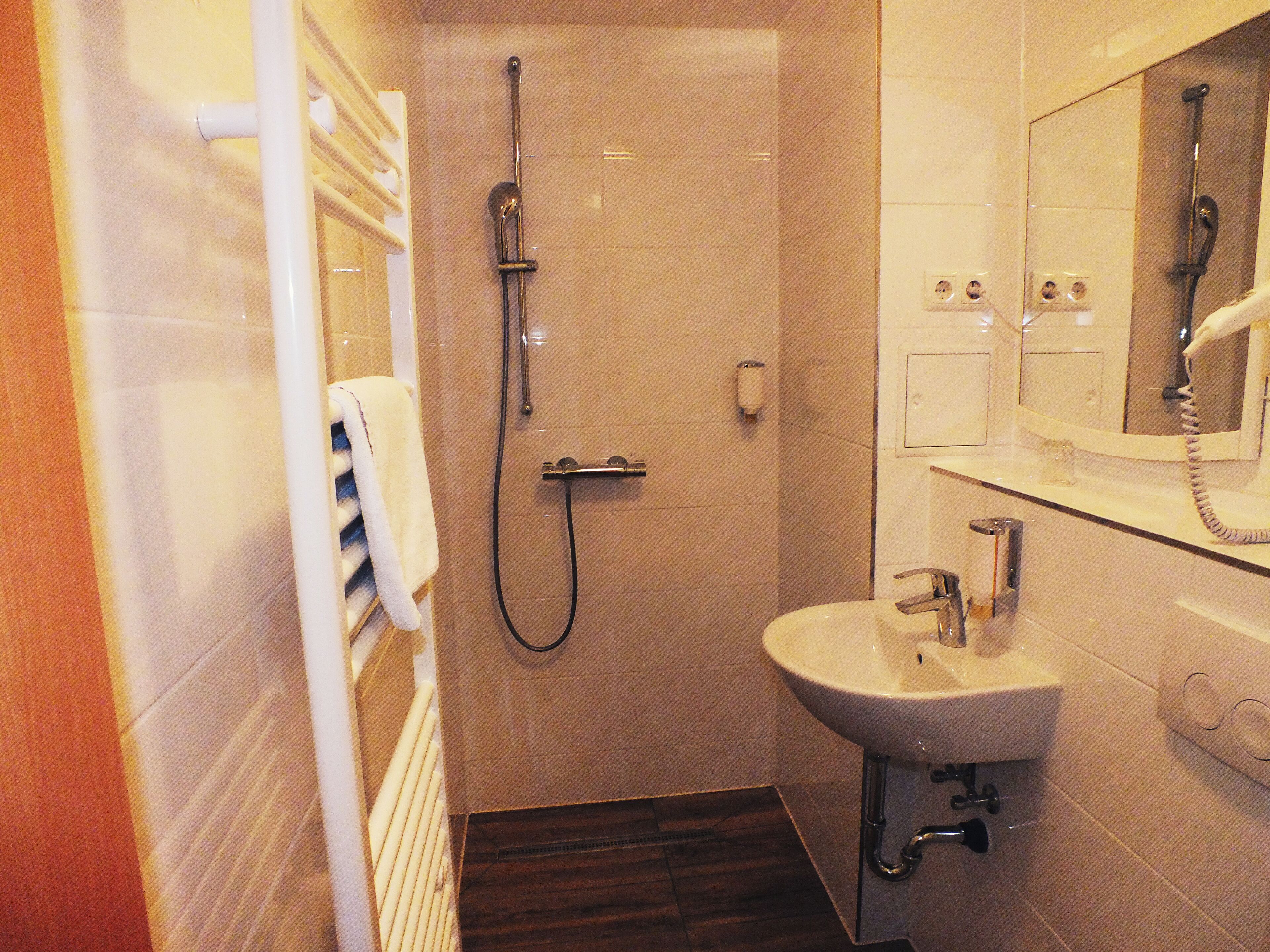 Une salle de bain avec une douche, un lavabo et un miroir.
