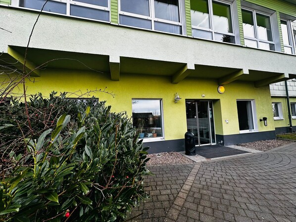 A building with a green facade, a black door, and a small window.