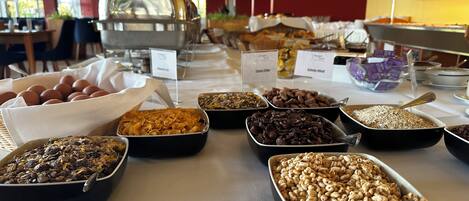 A buffet table with various food items including eggs, cereal, and nuts.
