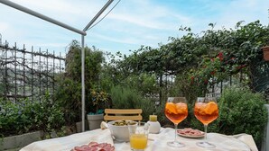 An outdoor dining setup with a table set for two, featuring plates of food, glasses of drink, and a bowl of olives. - Littardi Smart Suite (Imperia)