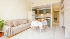 A compact living space with a sofa, dining table, and kitchenette. - Littardi Smart Suite (Imperia)