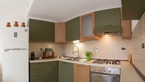 A kitchen with green cabinets, a white refrigerator, a stove, and a sink. - Littardi Smart Suite (Imperia)