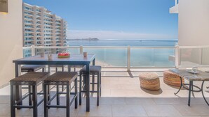 Ein Balkon mit Tisch, Stühlen und einem kleinen Beistelltisch mit einem Glas.