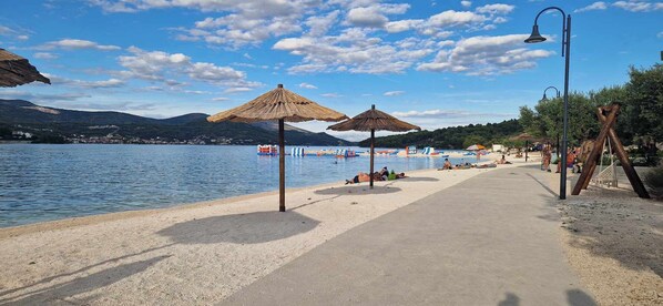 Ein Strand mit Sonnenschirmen, blauem Himmel und ruhiger See.
