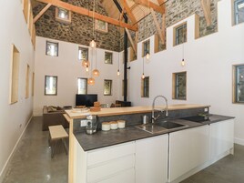 Una cocina moderna con una isla central, armarios empotrados y una pared decorativa de piedra.