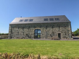 Un edificio de piedra con techo inclinado y un amplio arco de entrada.