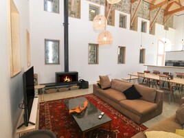 Una sala de estar acogedora con chimenea, un sofá, una mesa de centro y un comedor con sillas y una mesa.