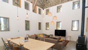 Un'ampia zona giorno con un tavolo da pranzo in legno, diverse sedie, un divano e un televisore.