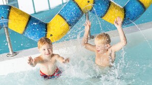Two children playing in a pool with water jets.