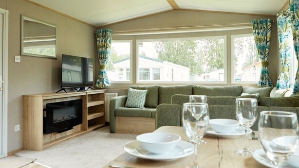 A cozy living area with a sofa, a TV, and a dining table set for four.