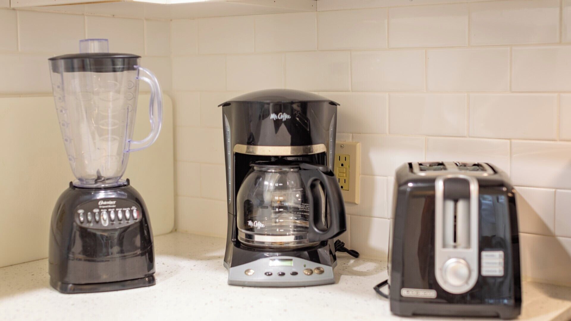 Un plan de travail de cuisine avec un mixeur, une machine à café et un grille-pain.