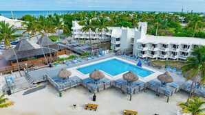 Een resort met een groot zwembad, ligbedden, parasols en uitzicht op de oceaan.