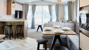 A modern kitchen with a dining area, bar stools, and a sofa. - HayIing Island Gold 2 Bed Caravan H002 (Hayling Island)