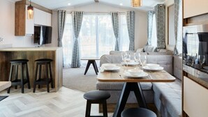 A modern kitchen with a dining area, bar stools, and a sofa.