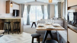 A modern kitchen with a dining area, bar stools, and a sofa.