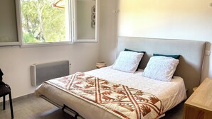 Une chambre à coucher avec un lit, un radiateur, une fenêtre et une table de chevet.