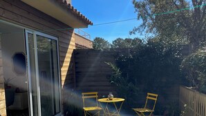 Une terrasse avec une table et des chaises, une porte-fenêtre coulissante et une clôture en bois.