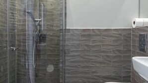 Une salle de bain avec une douche à parois de verre, des toilettes et un lavabo.