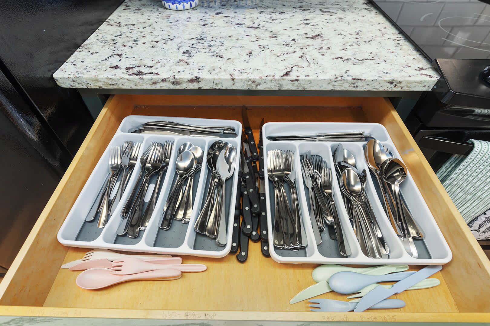 A kitchen drawer with two compartments containing silverware and utensils.