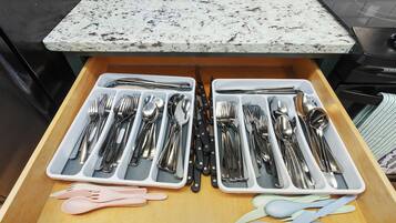 A kitchen drawer with two compartments containing silverware and utensils.