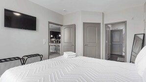 A hotel room with a bed, a TV, a mirror, and a kitchenette. - 2 King Beds Apartment_Great Amenities_Sleeps 4 (Olathe)