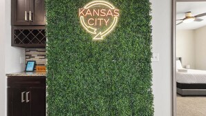 A wall with a neon sign reading "KANSAS CITY" and a green leafy wall. - 2 King Beds Apartment_Great Amenities_Sleeps 4 (Olathe)