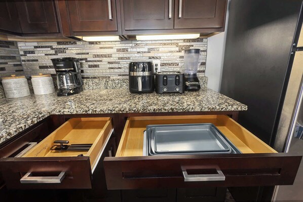 A kitchen with dark wooden cabinets, a granite countertop, and a built-in blender.