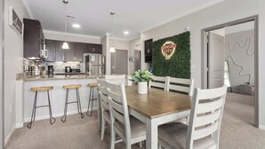 A modern kitchen with stainless steel appliances, a bar area with stools, and a dining table with chairs. - 2 King Beds Apartment_Great Amenities_Sleeps 4 (Olathe)